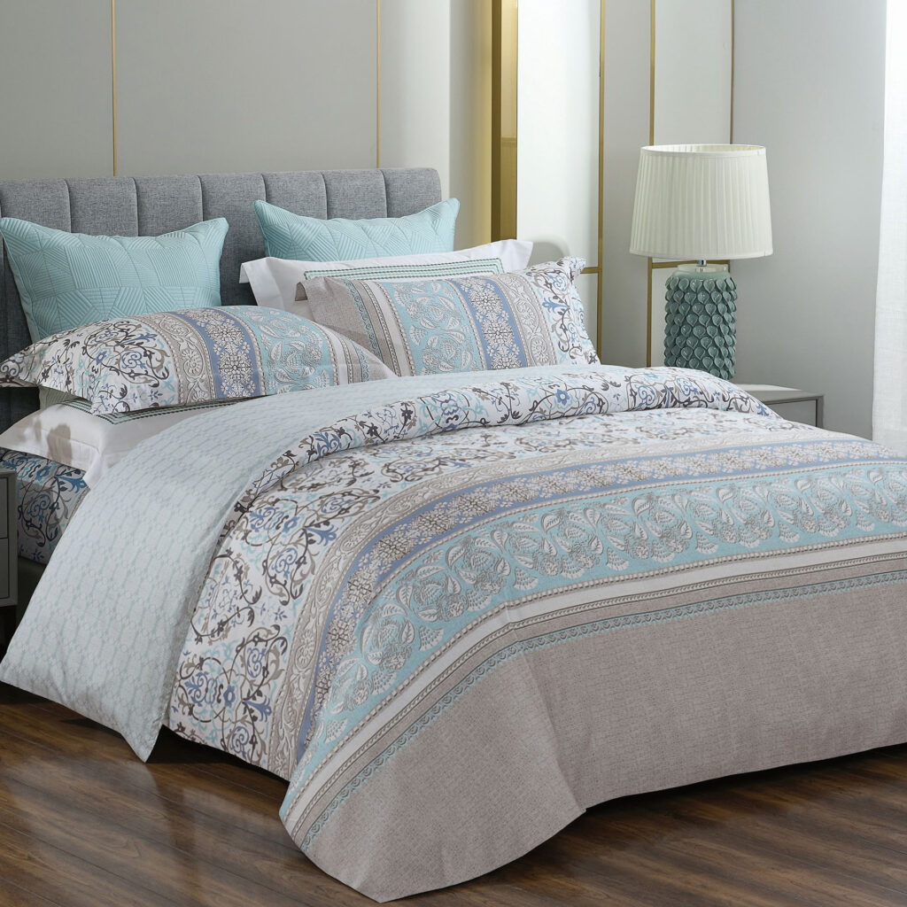 A set of fancy blue pattern bedding sheet displayed in the bedroom. There is a pillow on the bed.