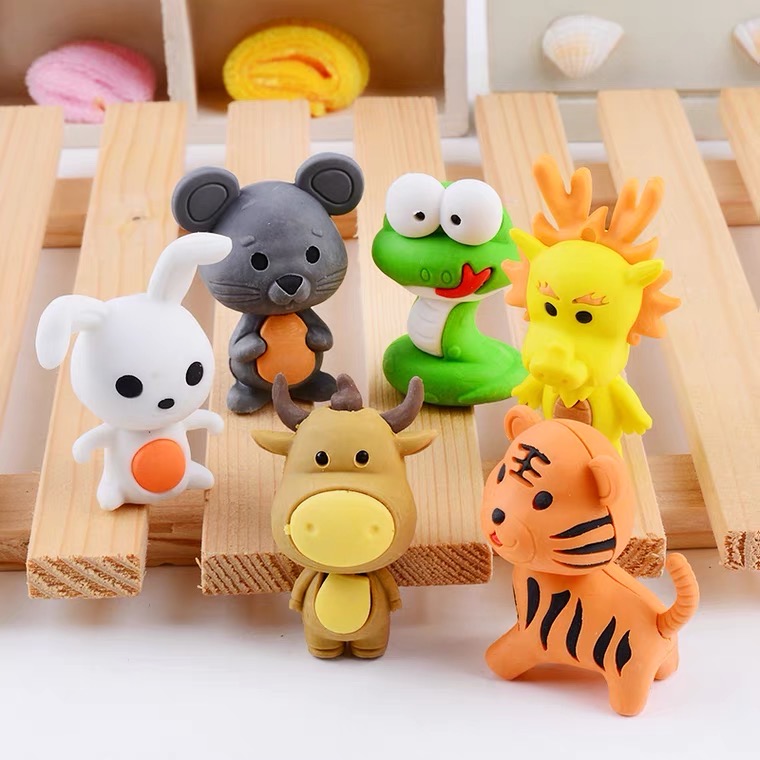 A set of plastic animal figurines on a wooden table. Including rabbit, mouse, snake, dragon, cow, and tiger.
