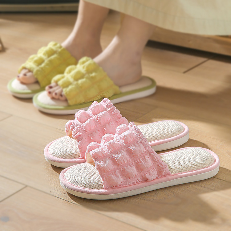 2 pairs of comfortable slippers. The pink slipper is at the front of the image, and the green slipper is at the back of the image with a person who is wearing it.