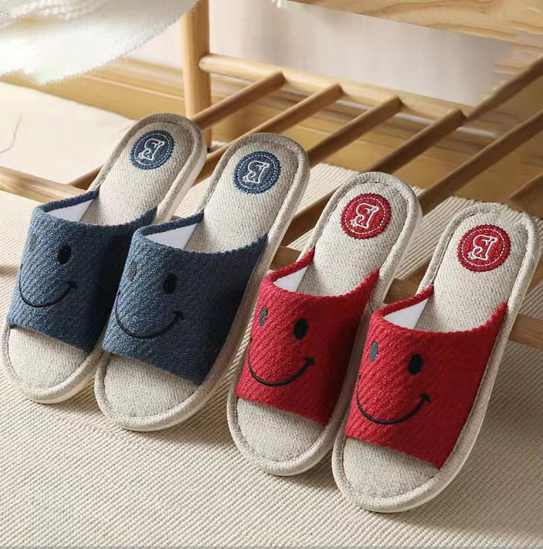 2 pairs of smile face comfortable slippers. The blue slipper is on the left of the image, and the red slipper is on the right of the image. On the slipper, there is a smile face on it.