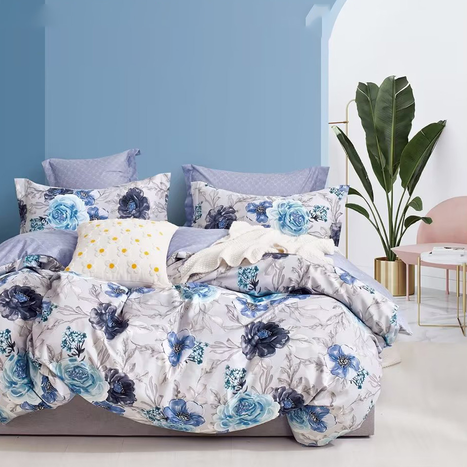 A set of blue rose pattern bedding sheet displayed in the bedroom. There is a white flower pattern cushion on the bed. This is an image of showing one's better living product.