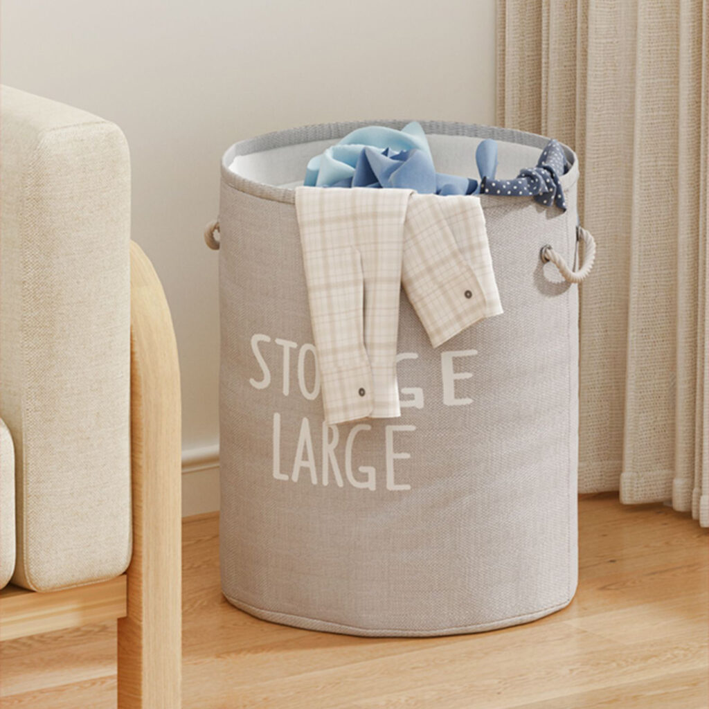 A grey laundry bag with text storage large fills with clothes.